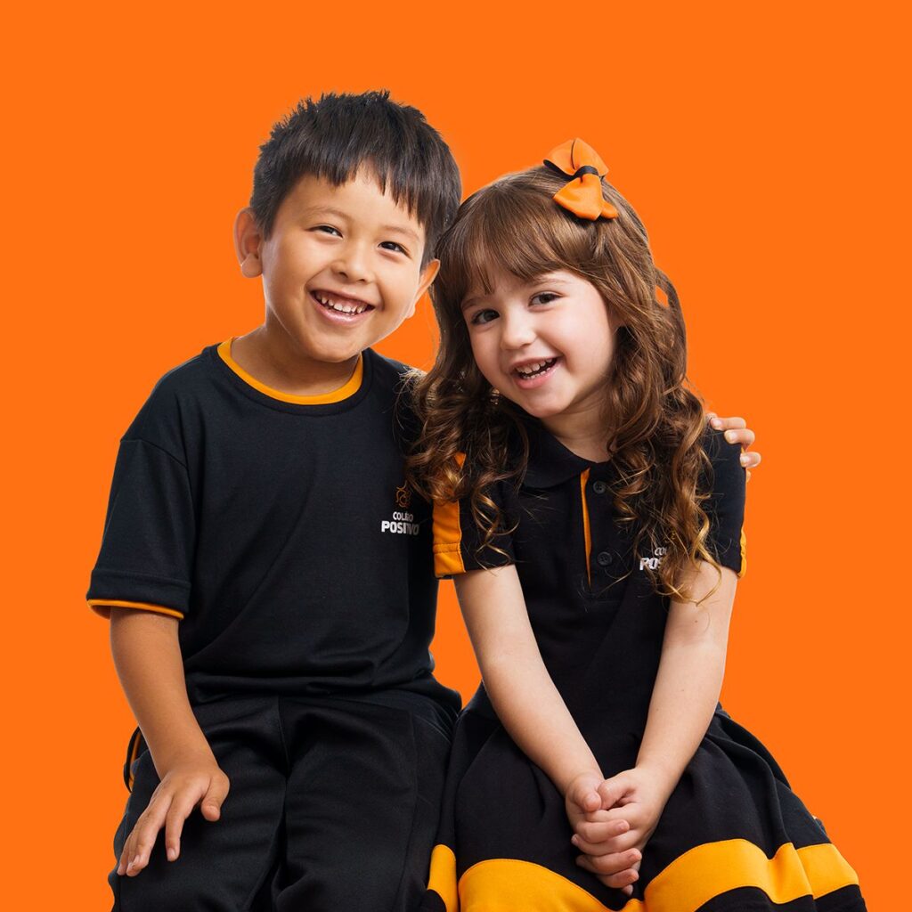 Crianças com uniforme escolar em fundo laranja, Positivo